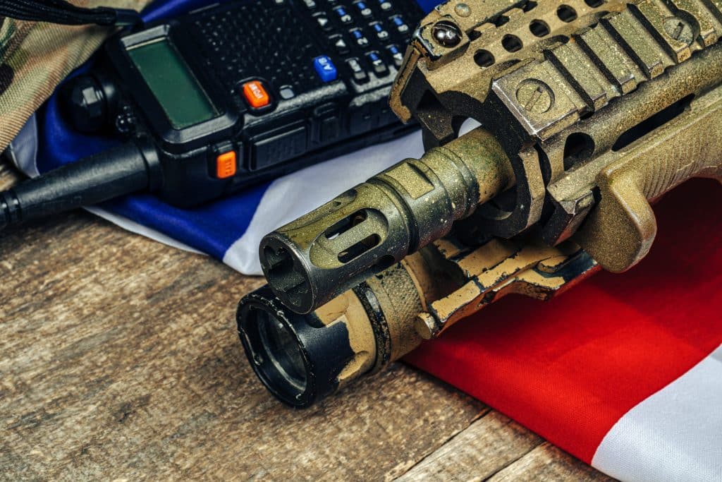 U.S. battle flag and assault rifle on the wooden table.